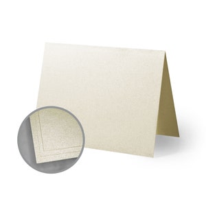 May include: A blank ivory card with a subtle shimmer finish. The card has a gold border and is folded in half.