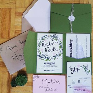 May include: A green and white wedding invitation with a floral wreath design. The invitation reads "Kristen & Pietro" and includes the date "June twenty-fourth, two thousand seventeen".