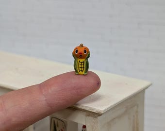 May include: A miniature Halloween-themed figurine. The figurine is a combination of a pumpkin and corn, with an orange pumpkin head and a green and yellow corn body. The figurine is small, measuring approximately 0.75 inches in height.