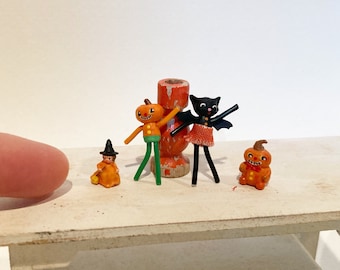 Könnte beinhalten: Ein Set mit fünf Halloween-Figuren, darunter eine Hexe, ein Kürbis, eine schwarze Katze und zwei Jack-o'-Lanterns. Die Figuren sind aus Holz und in Orange, Grün, Schwarz und Weiß bemalt.
