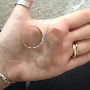 May include: Three silver metal rings of different sizes, lying on a person's hand.