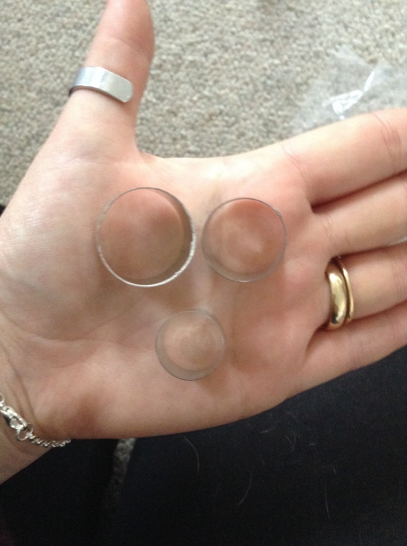 May include: Three silver metal rings of different sizes, lying on a person's hand.