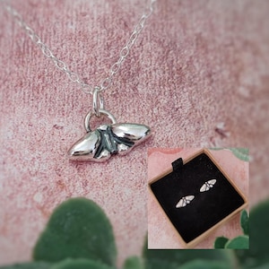 Peut inclure: Un collier en argent avec un petit pendentif en forme de papillon et des boucles d'oreilles à papillon assorties dans une boîte noire.