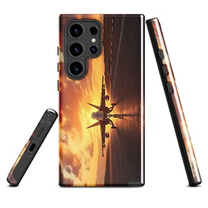 Puede incluir: Una funda para teléfono con una puesta de sol y un avión de combate despegando en una pista. La funda del teléfono es negra con una parte posterior transparente.
