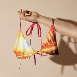 May include: A colorful bikini top with a tie-dye pattern in shades of orange, yellow, and pink. The top has adjustable straps and a tie closure at the back.