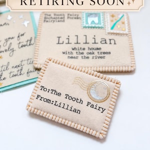Puede incluir: Un sobre rectangular de fieltro beige con bordes cosidos. El frente presenta el texto 'To: The Tooth Fairy' y 'From: Lillian' con un sello circular de luna en oro y plata. Un sobre más grande detrás está dirigido a Lillian.