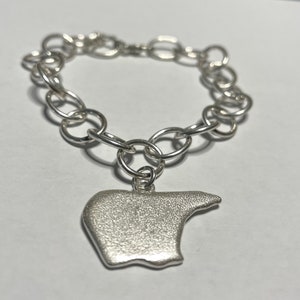 May include: A silver charm bracelet with a silver charm in the shape of a bear. The bracelet is made of a chain link design.
