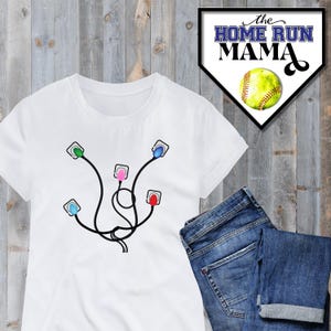 Könnte beinhalten: Weißes T-Shirt mit einer Grafik von fünf bunten Steckdosen, die durch Drähte verbunden sind. Der Text "the HOME RUN MAMA" befindet sich auf einem baseballförmigen Hintergrund.