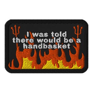 Könnte beinhalten: Gestickter Aufnäher mit dem weißen Text "I was told there would be a handbasket" auf schwarzem Hintergrund. Mit orangefarbenen Flammen und einem Dreizack auf jeder Seite.