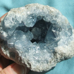 May include: A blue celestite geode with a rough exterior and a hollow interior lined with sparkling blue crystals.