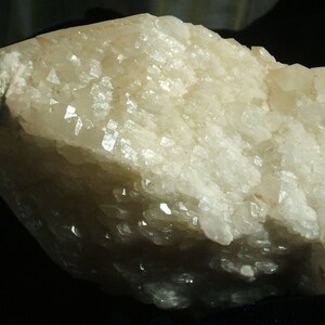 May include: A large, white, translucent quartz crystal cluster with a rough, textured surface. The crystal has a natural, raw appearance.