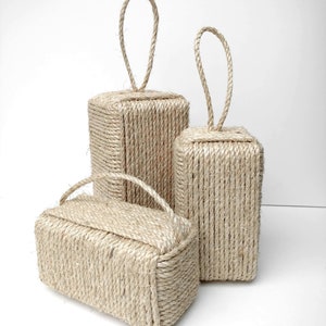 May include: Three natural rope doorstops in different sizes. The doorstops are made of thick, natural rope and have a loop handle at the top.