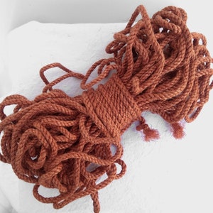 May include: A large coil of thick, brown rope made from natural fibers. The rope is coiled and tied together in the center.