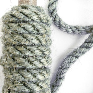 May include: A spool of thick, green rope with a brown wooden center. The rope is made of natural fibers and has a rough texture.