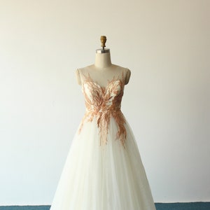 Vestido de noiva em tule champanhe com corte em A: apliques de renda dourada, costas abertas