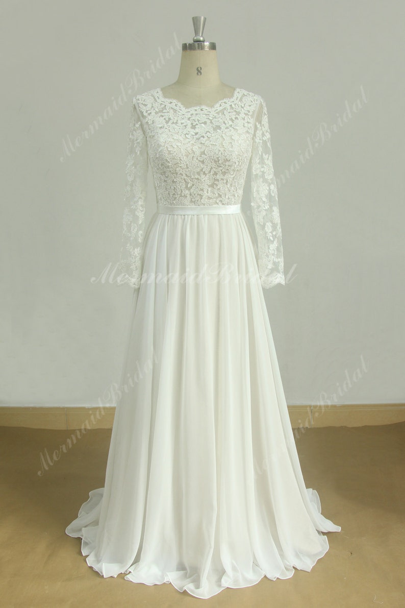 May include: A white lace wedding dress with long sleeves and a chiffon skirt. The dress has a fitted bodice and a flowing skirt.