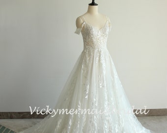 May include: A white off-the-shoulder wedding dress with a lace bodice and a tulle skirt. The dress has a floral pattern and a train.