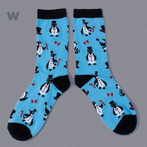 May include: A pair of blue socks with a black penguin pattern. The penguins are wearing top hats and bow ties. The socks have black cuffs.