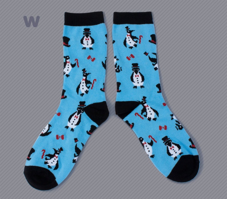 May include: A pair of blue socks with a black penguin pattern. The penguins are wearing top hats and bow ties. The socks have black cuffs.