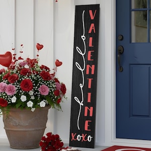 May include: A Valentine's Day porch scene with red and pink balloons, a large floral arrangement, and a welcome mat. A black sign reads "VALENTINE" in white script with "xoxo" at the bottom. A red bow adorns a black lantern.
