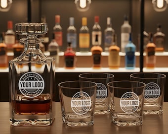 May include: A clear glass decanter with a square base and a stopper, filled with amber liquid, sits on a wooden surface. Four matching lowball glasses are arranged around it. Each glass and the decanter feature a "YOUR LOGO" placeholder.