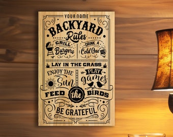 May include: A wooden sign with the text "YOUR NAME BACKYARD Rules" and a list of rules for enjoying the backyard, including grilling burgers, drinking a cold one, laying in the grass, playing games, enjoying the sun, feeding the birds, and being grateful.