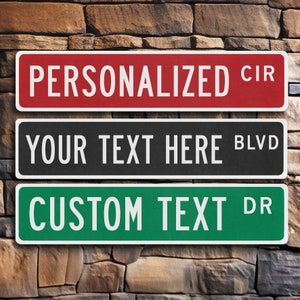 May include: Three personalized street signs with white text on a red, black, and green background. The top sign reads "PERSONALIZED CIR", the middle sign reads "YOUR TEXT HERE BLVD", and the bottom sign reads "CUSTOM TEXT DR".