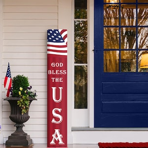 May include: A red, white, and blue porch sign with the words "God Bless The USA" and an American flag design.