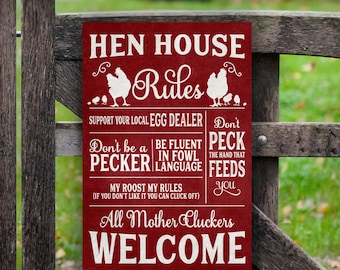 Op de afbeelding: Een rood bord met witte tekst dat "Hen House Rules" zegt. Het bord heeft een kippensilhouet en de tekst "Support your local egg dealer". Het heeft ook regels zoals "Don't be a pecker", "Be fluent in fowl language", en "Don't peck the hand that feeds you". Het bord eindigt met de tekst "All Mother Cluckers Welcome".