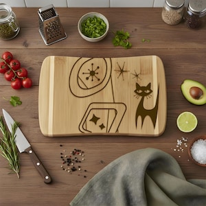 May include: A bamboo cutting board with a mid-century modern design, featuring a stylized cat and geometric shapes. The board is surrounded by fresh ingredients like tomatoes, herbs, and avocado, suggesting a culinary theme.