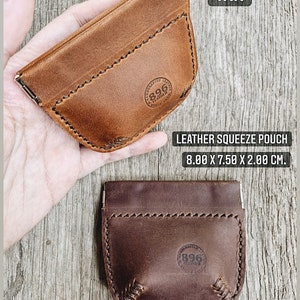 May include: Two leather squeeze pouches, one tan and one dark brown. Both pouches have a stitched design and a circular logo with the text "896 Leather" inside. The pouches are 8 inches by 7.5 inches by 2 inches.
