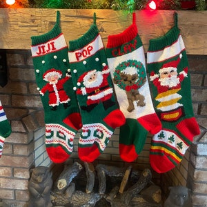 May include: Four green, red, and white knitted Christmas stockings with Santa Claus, a reindeer, and a snowman designs. The stockings are hung on a wooden mantel above a fireplace.
