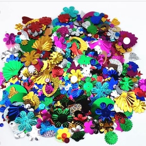 May include: A large assortment of colorful, metallic sequins in various shapes, including flowers, stars, moons, and leaves. The sequins are perfect for crafting and decorating.