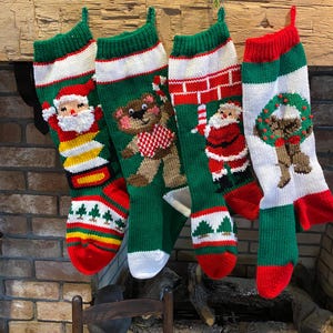 May include: Four knitted Christmas stockings with different designs. The stockings are green, red and white with a variety of festive themes including Santa Claus, a teddy bear and a wreath.