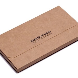 May include: A brown cardboard box with the text "Happer Studio leather accessories" printed on the front.