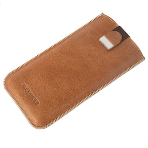 May include: A brown leather phone case with a white stitching detail and a silver clasp. The case has the word "ALEXANDER" embossed on the front.