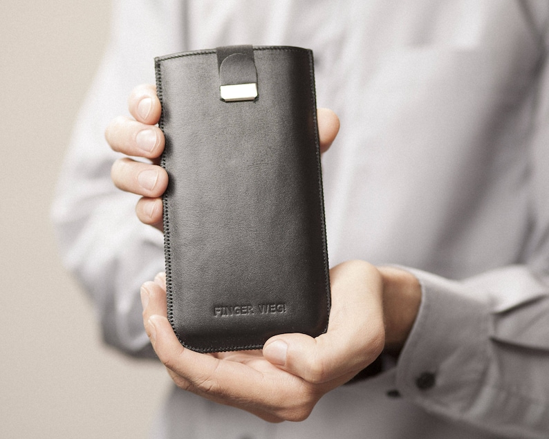 May include: A black leather phone case with a silver clasp and the text "FINGER WEG" embossed on the front.