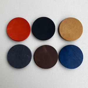 Peut inclure: Six sous-verres ronds de différentes couleurs : rouge, noir, marron, bleu et deux nuances de marron. Les sous-verres sont faits d’un matériau lisse et texturé.