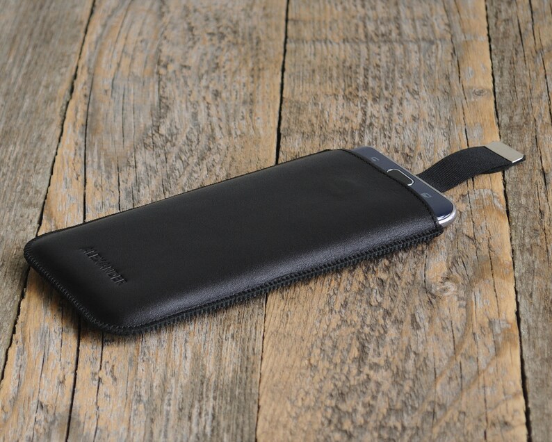 May include: Black leather phone case with a zipper and a strap. The case has the word "ARCTIC" embossed on the front.