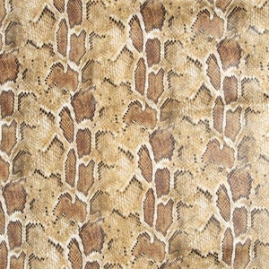 Peut inclure: Un tissu texturé présentant un motif répétitif de peau de serpent dans des tons de beige, de brun clair et de brun foncé. La surface affiche un design organique complexe rappelant des écailles avec des formes irrégulières et des contours noirs.