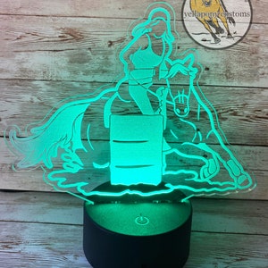 May include: A green LED night light shaped like a barrel racer riding a horse. The light is on a black base with a power switch. The text "www.yellaponycustoms.com" is at the bottom of the image.