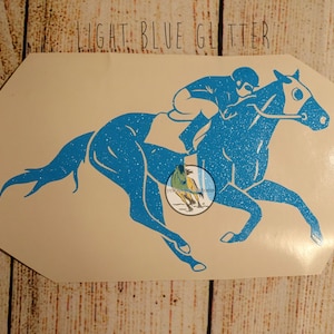 May include: Light blue glitter vinyl decal of a horse and rider. The horse is running and the rider is wearing a helmet.