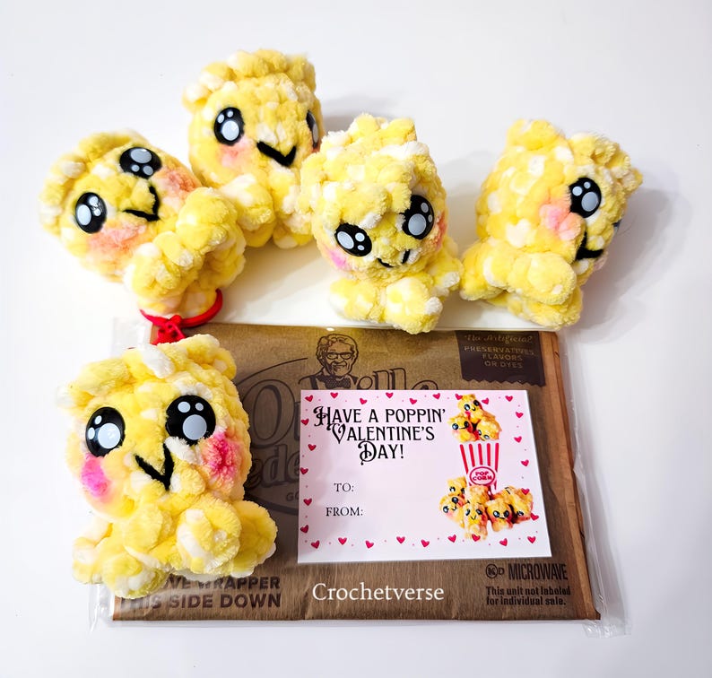 May include: Five handmade yellow popcorn plushies with black eyes, pink cheeks, and smiling faces. A Valentine's Day card with the text "Have a Poppin' Valentine's Day!" is included. The plushies are on a brown package.