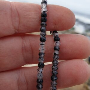 May include: Two strands of black and clear beaded jewelry. The beads are faceted and have a dark, almost black, color. The beads are strung on a clear elastic cord.