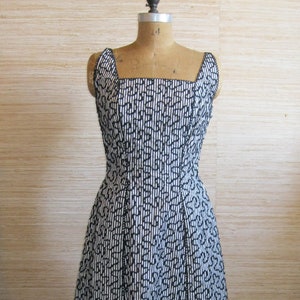 May include: A black and white striped dress with a square neckline and a fitted bodice. The dress is on a dress form and has a full skirt.
