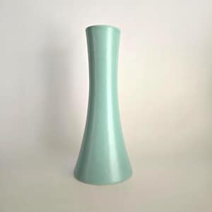 May include: A tall, light-green vase with a flared base and a slender, cylindrical neck. The vase has a smooth, glossy finish and a simple, elegant design. The vase is approximately 10 inches tall.