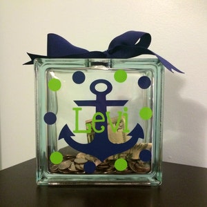 May include: A glass jar with a blue anchor and the name "Levi" on it. The jar is decorated with green and blue polka dots and has coins inside.