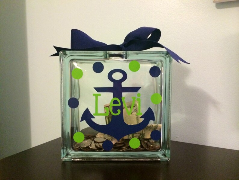 May include: A glass jar with a blue anchor and the name "Levi" on it. The jar is decorated with green and blue polka dots and has coins inside.