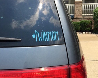 May include: A gray minivan with a blue decal on the back window that says "#twinmom".