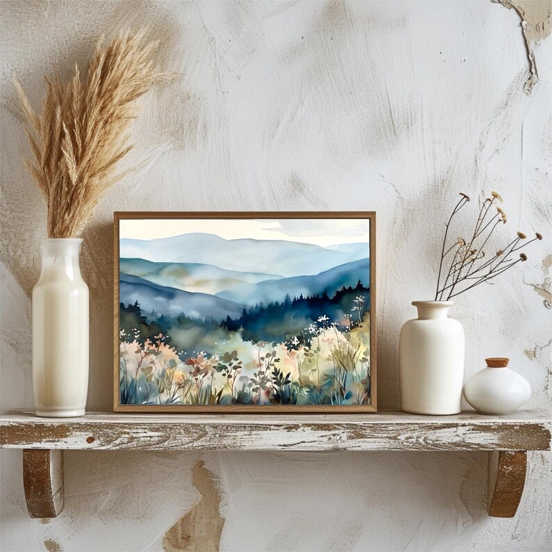 May include: A framed watercolor painting of a misty mountain landscape with a foreground of blue and green trees and white flowers.